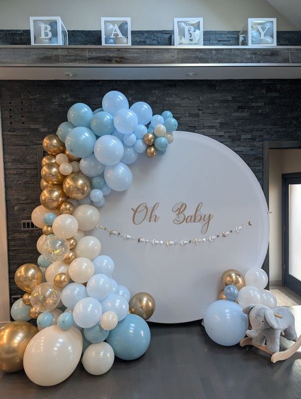 Balloon garland in blue, cream and gold beside a round backdrop